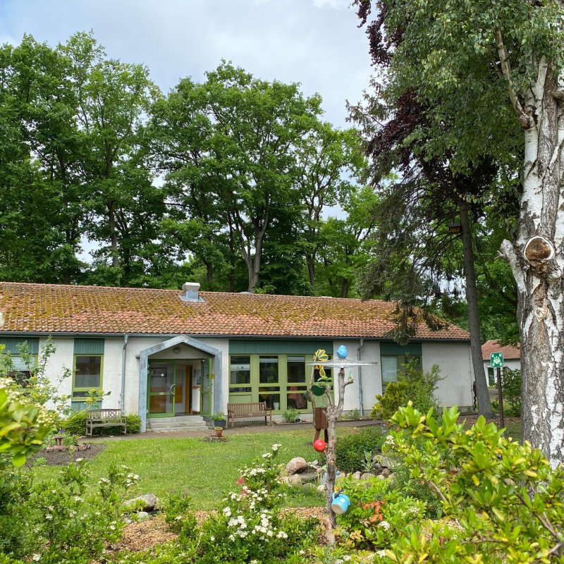 Das Haus der Möbelbörse eingebettet in alte Bäume und einen schönen grünen Garten.