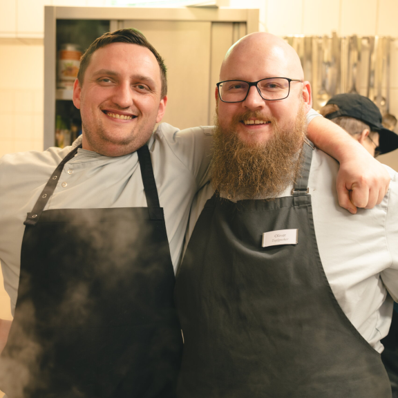 lachende Köche des Bistros stehen eng zusammen in der Küche