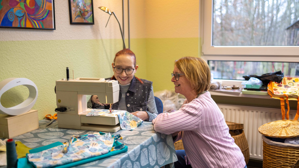 Zwei Frauen sitzen lächelnd an eine Nähmaschine