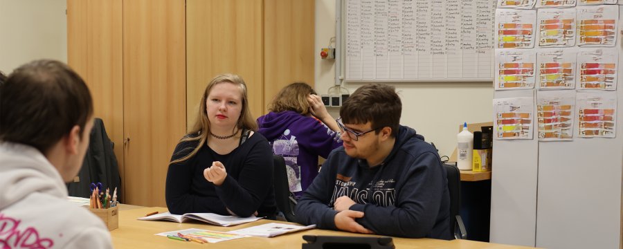 Eine Gruppe junger Menschen sitzt am Tisch und lernt.