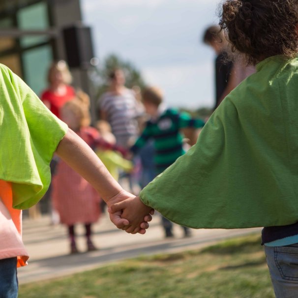 Kleine Kinder halten sich an den Händen und spielen im Freien