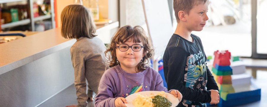 Ein Kind mit seinem Mittagessen in der Kita.