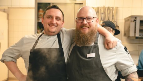lachende Köche des Bistros stehen eng zusammen in der Küche