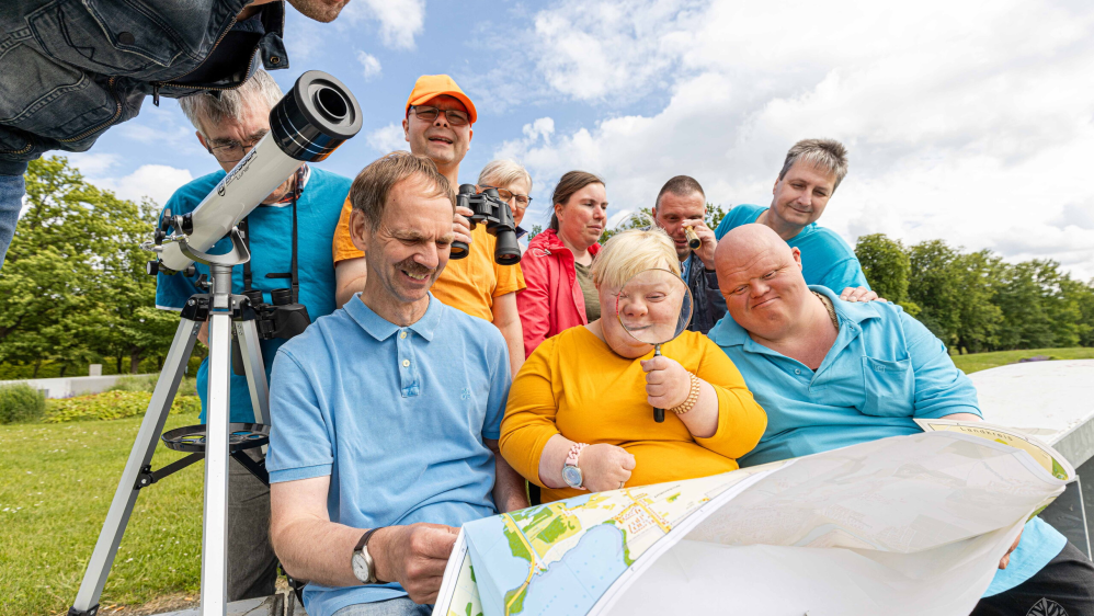 Eine Gruppe von Menschen  mit Unterstützungsbedarf schaut sich einen Stadtplan an.