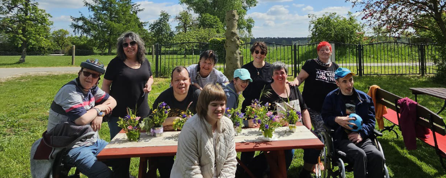 Eine Gruppe von Menschen sitzt an einem Picknicktisch und genießt die Zeit zusammen im Freien.