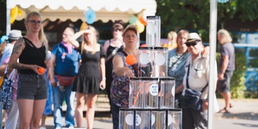 Männer und Frauen beim Dosenwerfen an einem sonnigen Tag