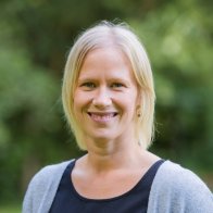 Nahaufnahme einer blonden Frau vor unscharfen grünem Hintergrund