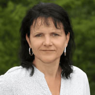 Nahaufnahme einer Frau mit dunklen Haaren vor grünem unscharfen Hintergrund