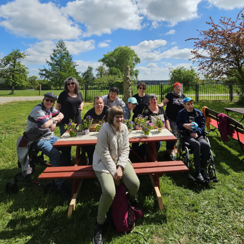 Eine Gruppe von Menschen sitzt an einem Picknicktisch und genießt die Zeit zusammen im Freien.