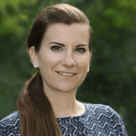 Nahaufnahme einer Frau mit dunklen langen Haaren vor einem grünen unscharfen Hintergrund