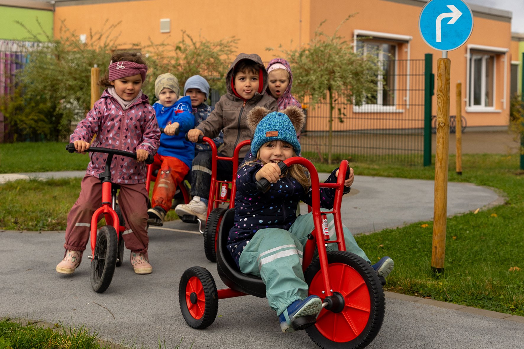 Kitakinder fahren auf Dreirädern durch einen Verkehrsgarten