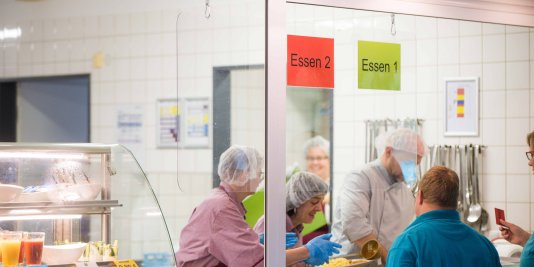 Mehrere Personen arbeiten zusammen in einer Küche und kochen.
