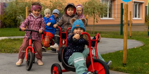 Kitakinder fahren auf Dreirädern durch einen Verkehrsgarten