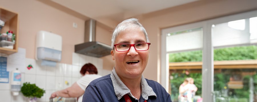 Eine frau mit Brille trocknet Geschirr ab.