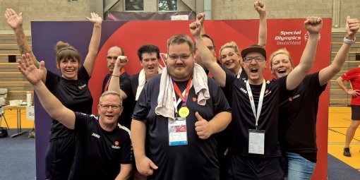 Ein Sportlerteam steht jubelnd in einer Turnhalle