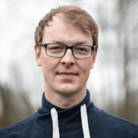 Nahaufnahme eines Mannes mit dunkler Brille vor unscharfen Hintergrund